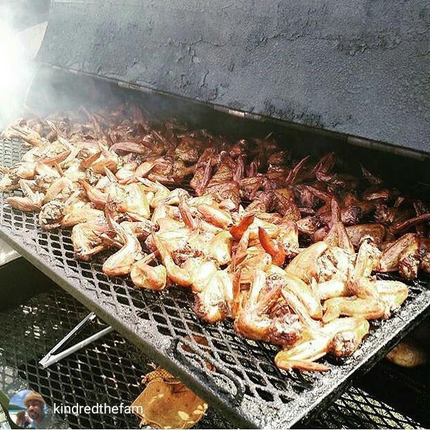 Close-up of jerk wings cooking in a large outdoor smoker